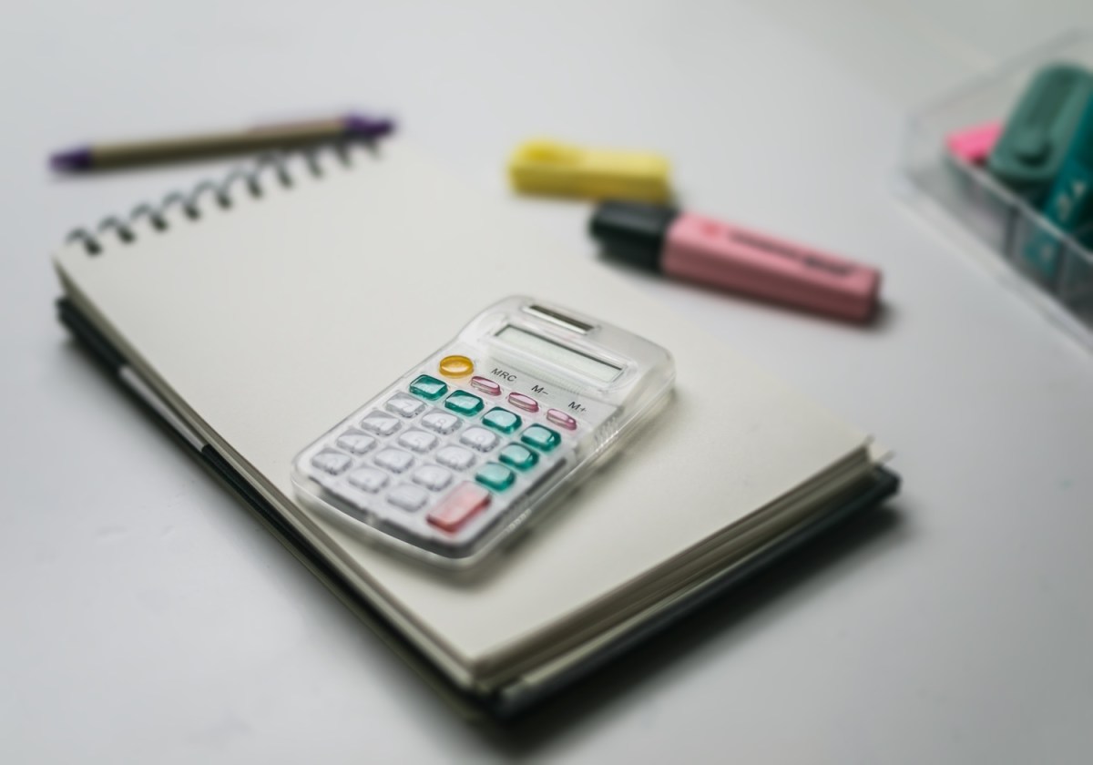 weißer Taschenrechner und Bleistift und einige Clips in Weiß.