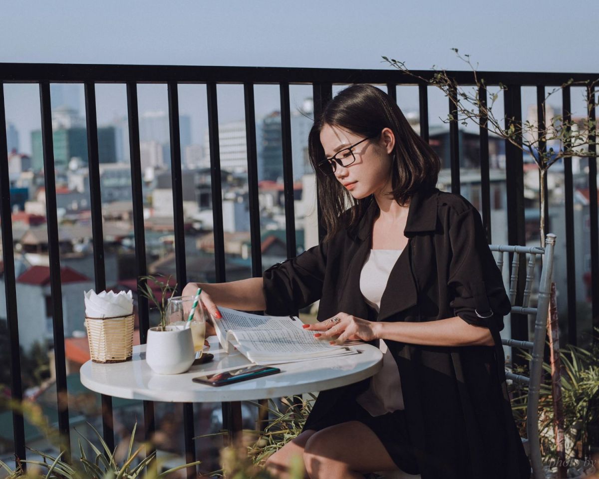 Frau sitzt auf einer Terrasse und liest ein Buch