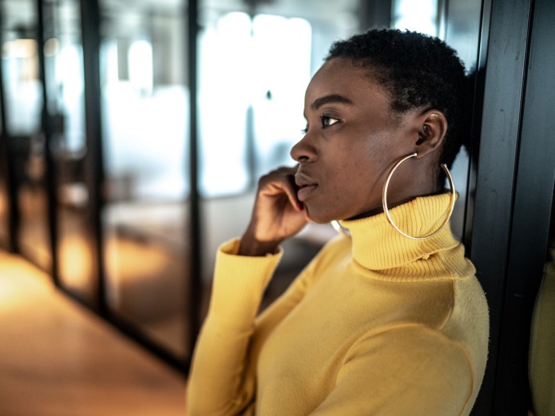 Junge Frau steht im Büro und sieht unzufrieden aus.