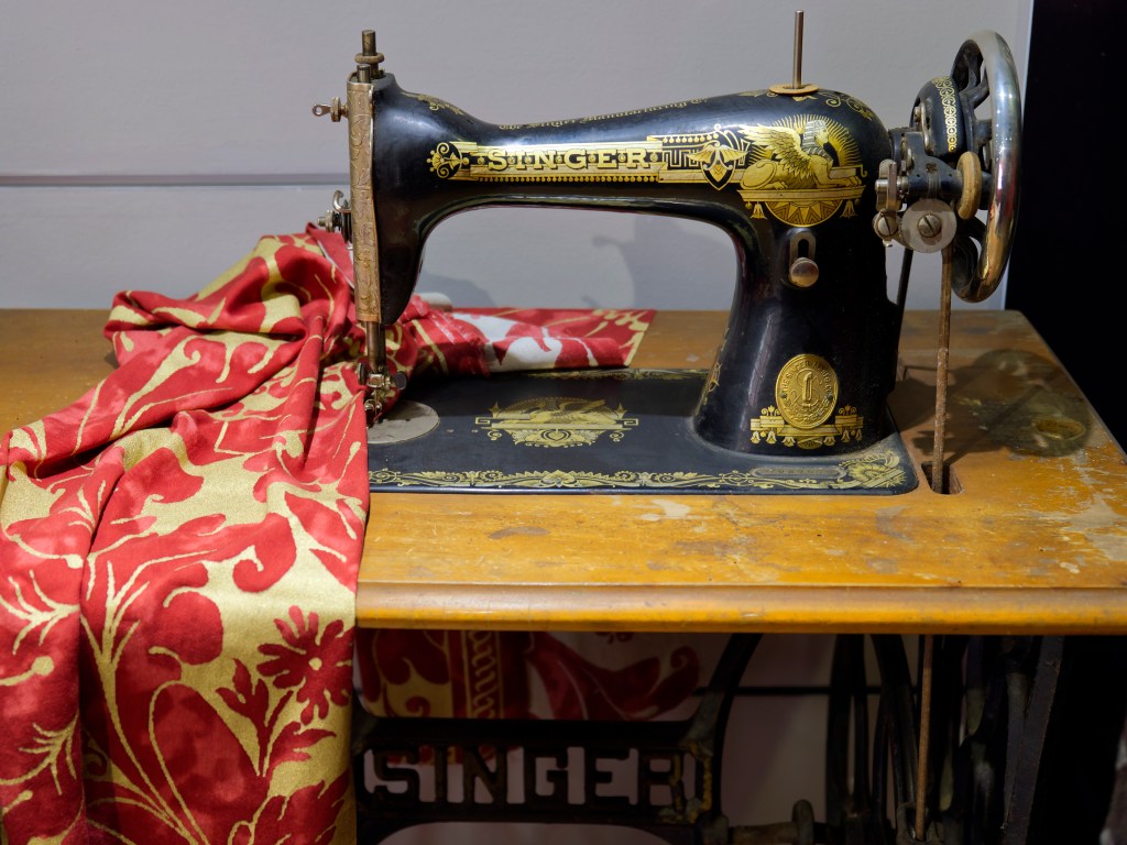 Antike Singer Nähmaschine steht auf einem Tisch mit Stoff
