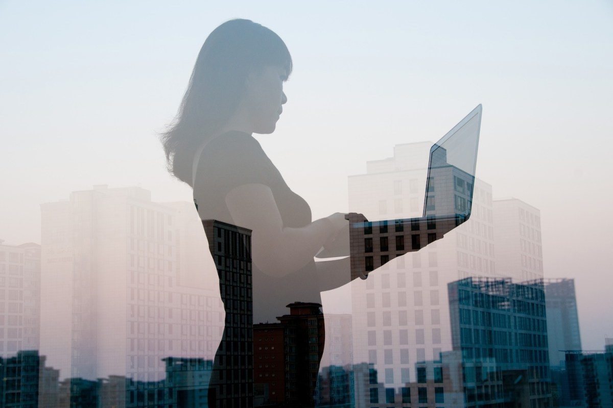 Doppelbelichtung einer Frau mit Laptop und Stadtlandschaft.