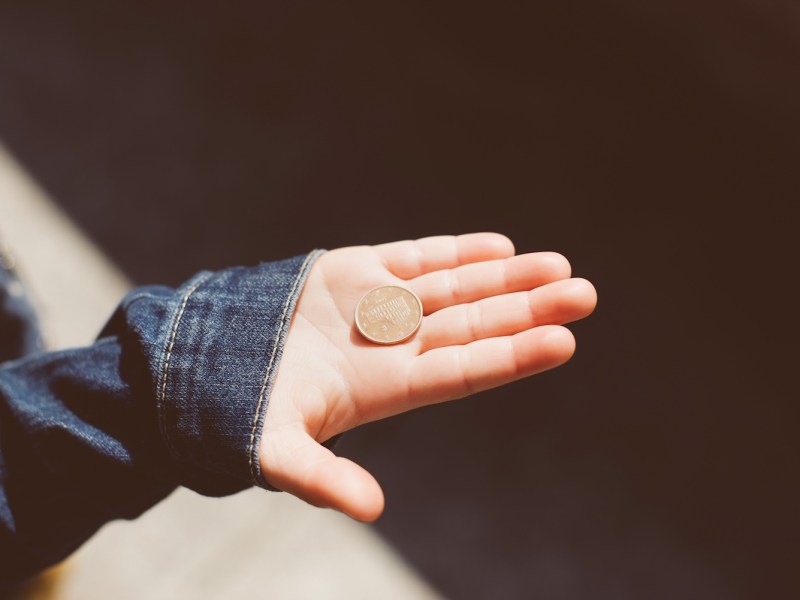 In einer Kinderhand liegt eine 5-Cent Münze.