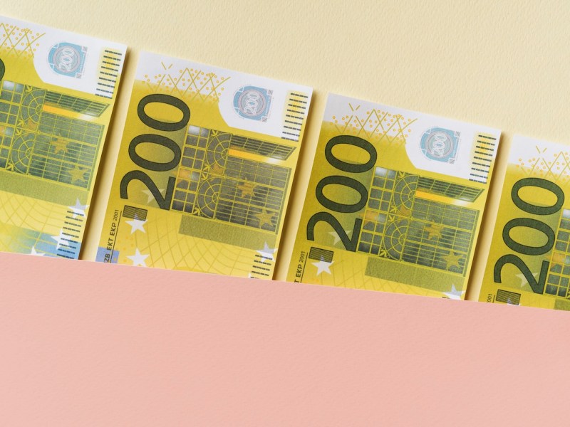 200-Euro Geldscheine auf pastellfarbenem Hintergrund.