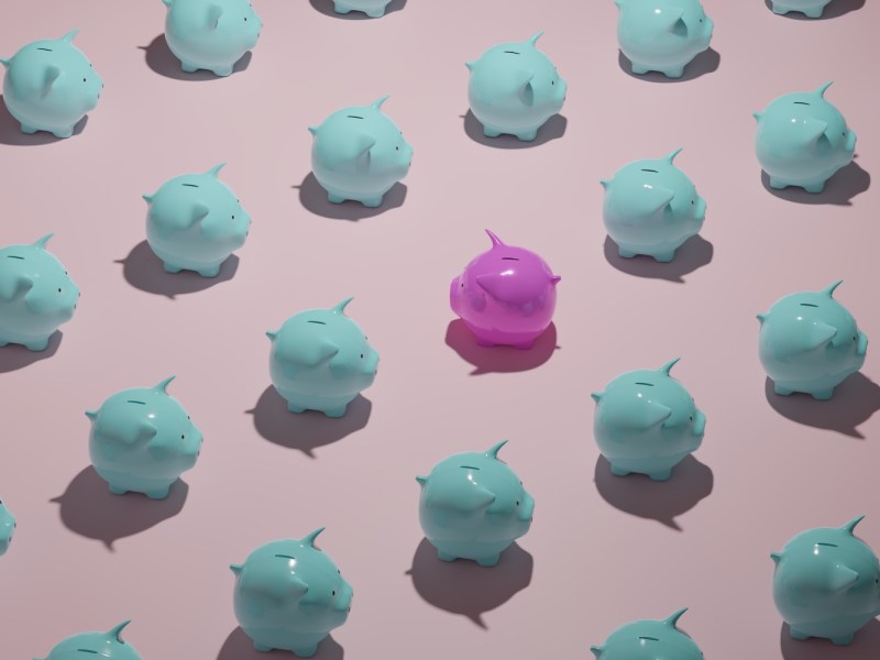 Ein rosa Sparschwein zwischen vielen blauen Sparschweine.