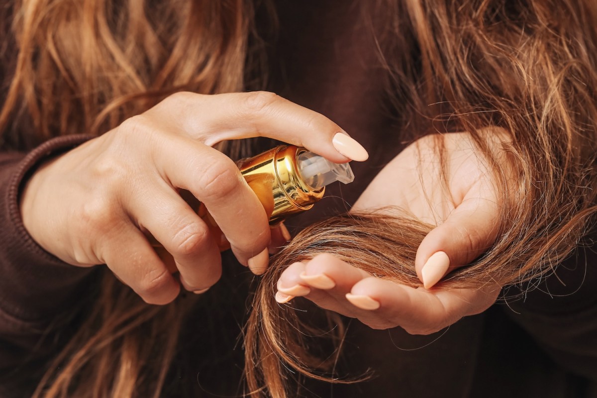 Eine Frau verwendet Haaröl in ihrem Haar.