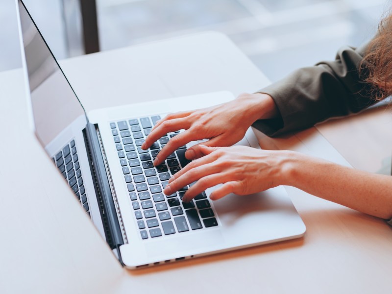 Eine Frau sitzt am Laptop und tippt.