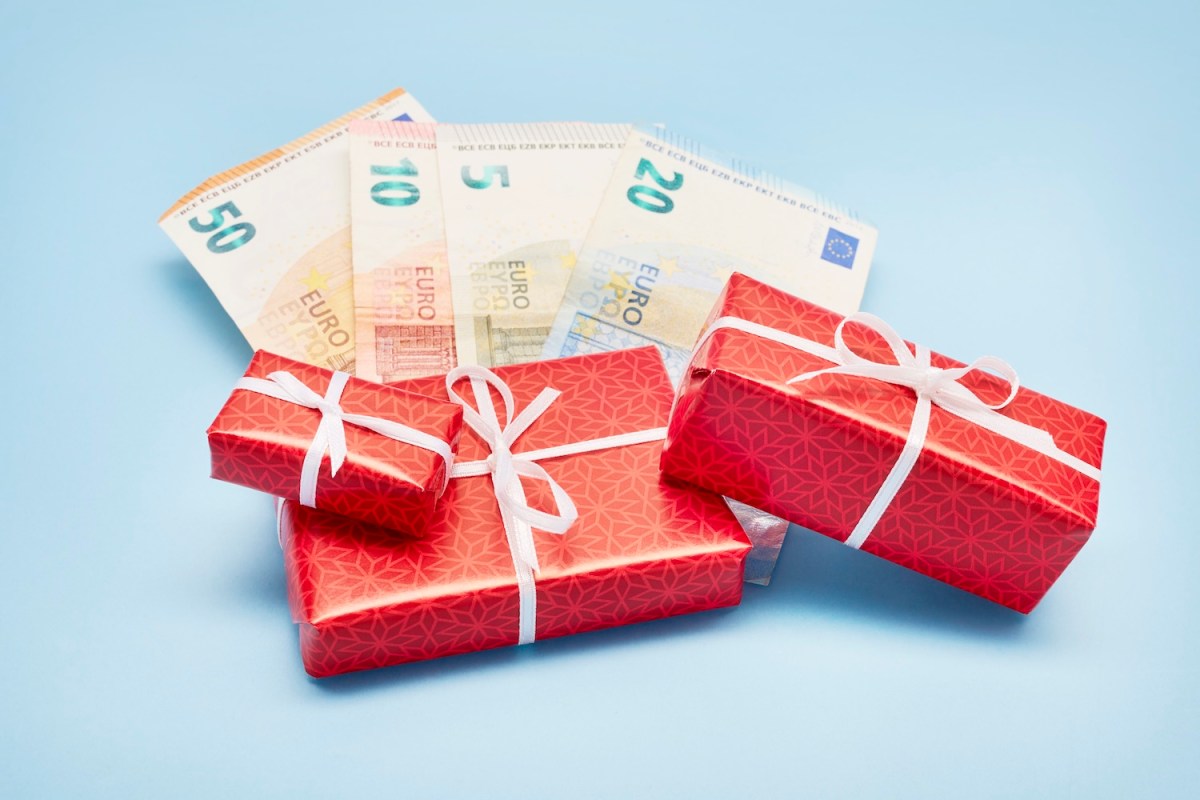 Draufsicht auf verpackte Weihnachtsgeschenke und Euro-Banknoten vor blauem Hintergrund