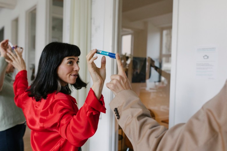 Eine Frau und ein Kollege balancieren einen Stift.