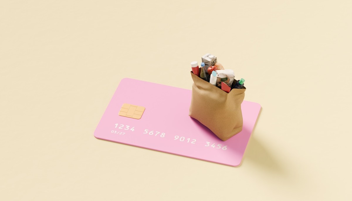 Eine Kreditkarte und eine Tasche gefüllt mit Lebensmitteln.